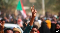 FILE - Pro-democracy protesters flash the victory sign as they take to the streets to condemn a takeover by military officials, in Khartoum, Sudan, Oct. 25, 2021. 