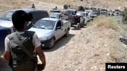 Des membres du Hezbollah escortent des réfugiés syriens à Arsal, Liban, le 12 juillet 2017. 