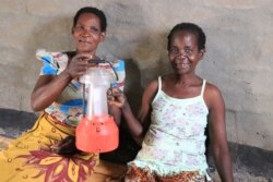 Diness Msampha, left, and Aliness Nepiyasi, Solar Mamas at Chatsala village in Lilongwe district, are excited after fixing a broken lantern.(Lameck Masina/VOA)