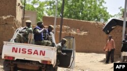 FILE - Burkinabe soldiers sit in a patrol pick-up car in Gorom Gorom, northern Burkina Faso, June 13, 2012. People were flocking to the town to flee a deadly attack on several villages on August 4, 2021. 