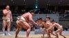 Retired Mongolian-born "yokozuna" wrestler Hakuho (far L), who now goes by the name Miyagino, watches as participants (R) try to push out Japanese wrestler Hakuoho (C) during a sumo class for youngsters on the sidelines of the 14th Hakuho Cup, a competiti