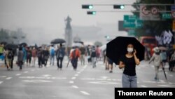 A woman wearing a mask walks past members of conservative civic groups who take part in an anti-government protest, as concerns over a fresh wave of the coronavirus disease (COVID-19) cases grow, in central Seoul, Aug. 15, 2020.