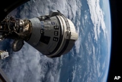 FILE - In this photo provided by NASA, Boeing's Starliner spacecraft is docked to the Harmony module of the International Space Station on July 3, 2024, seen from a window on the SpaceX Dragon Endeavour spacecraft docked to an adjacent port.