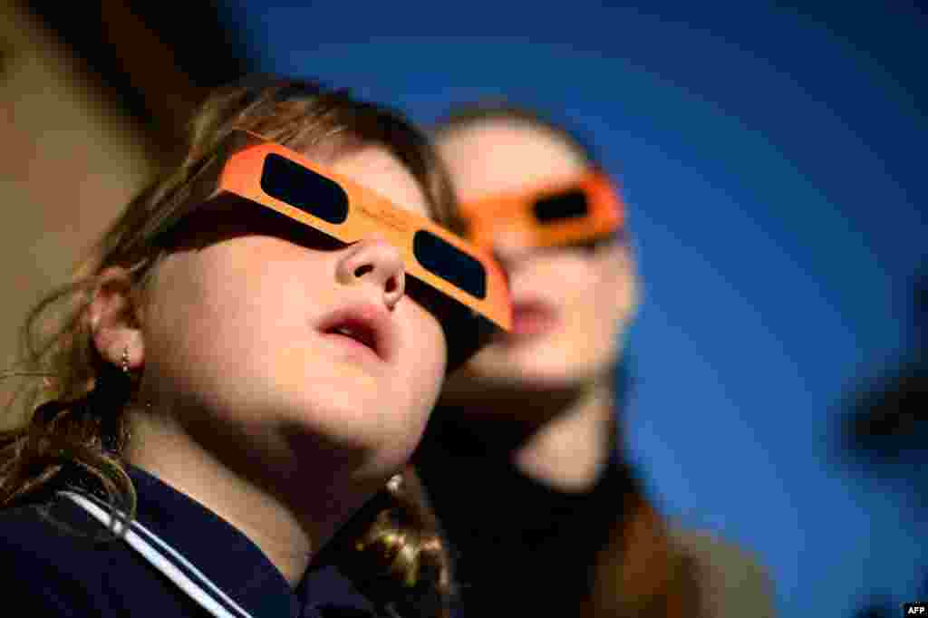 A child (L) watches a partial solar eclipse with a woman at the Sydney Observatory. Star-gazers were treated to an annular solar eclipse in remote areas of Australia with the moon crossing in front of the Sun and blotting out much of its light.