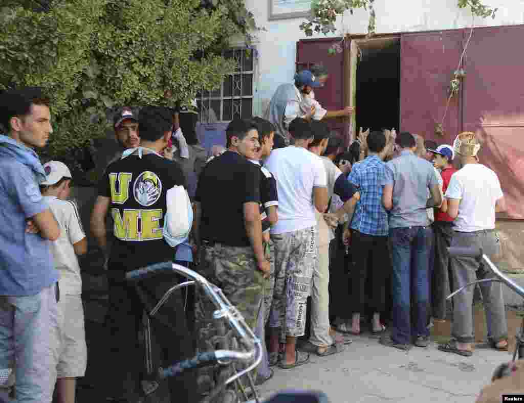 People stand in a line to receive water in Damascus, July 15, 2013. 