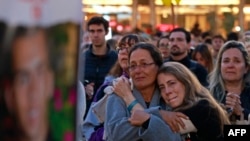 Apoiantes e familiares de reféns mantidos em cativeiro na Faixa de Gaza por militantes palestinianos abraçam-se enquanto assistem a uma transmissão televisiva em direto sobre a libertação de reféns israelitas, na Praça dos Reféns, em Telavive, a 19 de janeiro. 2025.