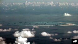 FILE - This aerial photo taken through a glass window of a military plane shows China's alleged on-going reclamation of Mischief Reef in the Spratly Islands in the South China Sea, May 11, 2015.