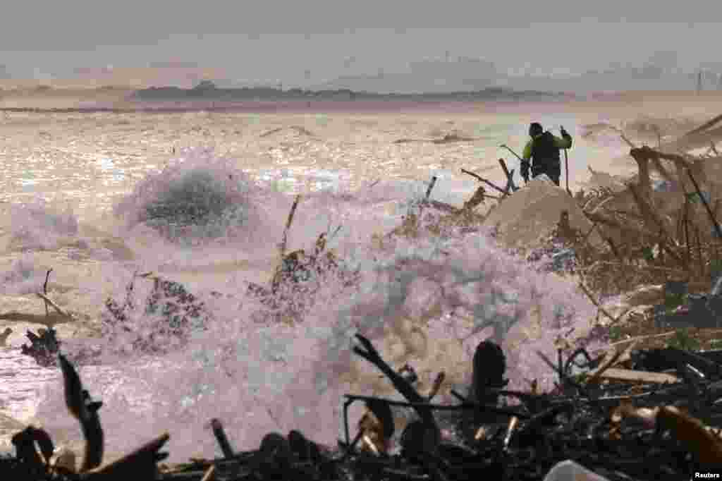 A volunteer walks as he looks for victims of the destruction on the shores of the Mediterranean Sea at the Saler beach, following heavy rains that caused floods, in El Saler, near Valencia, Spain.