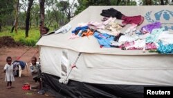 FILE - Children stand beside tents a refugee camp in Lovua, Angola, Sept. 13, 2017. 