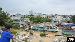 Seorang pria berdiri di Jembatan Long Bien Bridge dan mengamati rumah-rumah yang sebagian terendam air banjir setelah disapu Topan Yagi di Hanoi, Vietnam, Selasa, 10 September 2024. (Foto: Nhac Nguyen/AFP)