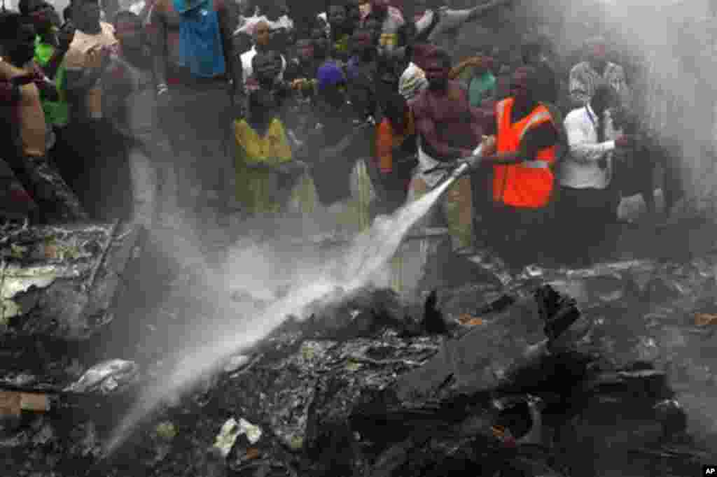 'Yan kallo sun taru yayin da 'yan kwana-kwana ke kokarin kashe wutar da ta barke a lokacin da jirgin saman kamfanin Dana Airlines wanda ya taso daga Abuja, ya fadi kan wani gida a Lagos, lahadi 3 Yuni, 2012.