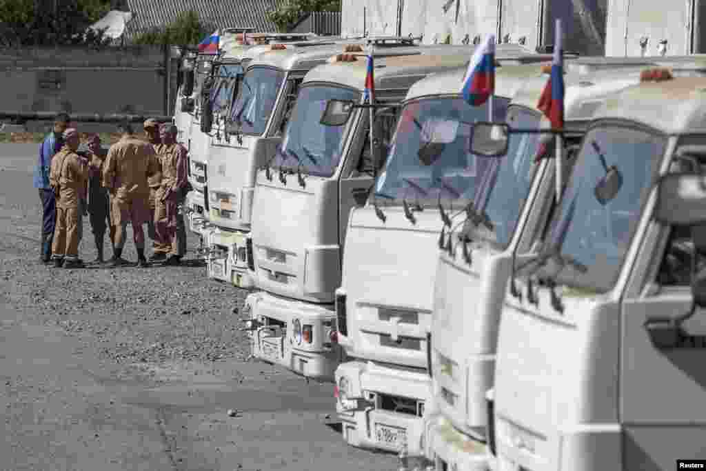 People stand near a Russian convoy of trucks carrying humanitarian aid in Donetsk, eastern Ukraine, Sept.0, 2014. 