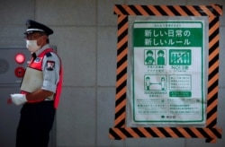 A station employee walks by a COVID-19 infection prevention instructions sign at a Tokyo metro station in Tokyo, Japan, July 30, 2021.