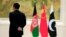 FILE - A security worker stands near, from left, Afghan, Chinese and Pakistani flags during the 1st China-Afghanistan-Pakistan Foreign Ministers Dialogue in Beijing, Dec. 26, 2017. China, Afghanistan and Pakistan over the past two years have launched a trilateral engagement at the foreign ministers level, and the three sides are scheduled to meet in Kabul for another round of talks later this year.