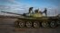 Ukrainian soldiers inspect a damaged Russian tank in the recently retaken village Chornobaivka near Kherson, Ukraine, Tuesday, Nov. 15, 2022. (AP Photo/Efrem Lukatsky)