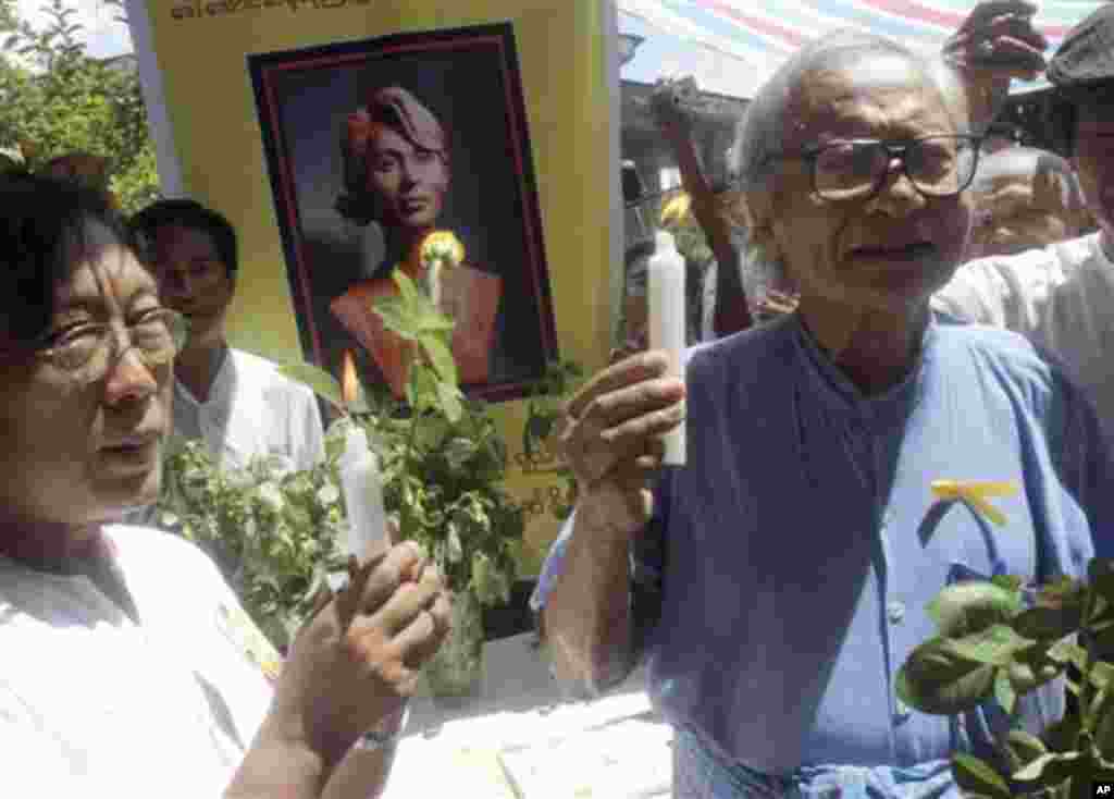 Win Tin, right, a senior leader of the National League for Democracy Party, and another party member, hold candles as they pray for release of Aung San Suu Kyi, their detained pro-democracy leader, at the home of a member of the party on Saturday, June 19