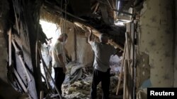 Residents remove debris inside a damaged building, which according to locals was caused by recent shelling, in Avdiivka in the Donetsk region, Ukraine, July 18, 2015.