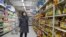 A shopper wearing a face mask browses an aisle of cooking oil in a supermarket in Beijing on Monday, March 16, 2020.