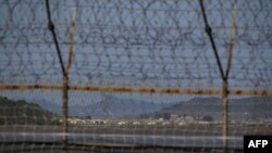 Sebuah desa Korea Utara terlihat di balik pagar Zona Demiliterisasi (DMZ) yang memisahkan Korea Utara dan Selatan, di pulau Gyodong Korea Selatan, 6 Oktober 2020. (Ed JONES / AFP)