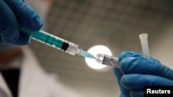 FILE - A medical worker holds a syringe with Sputnik V vaccine against the coronavirus disease at a vaccination center in St. Petersburg, Russia. Feb. 24, 2021.