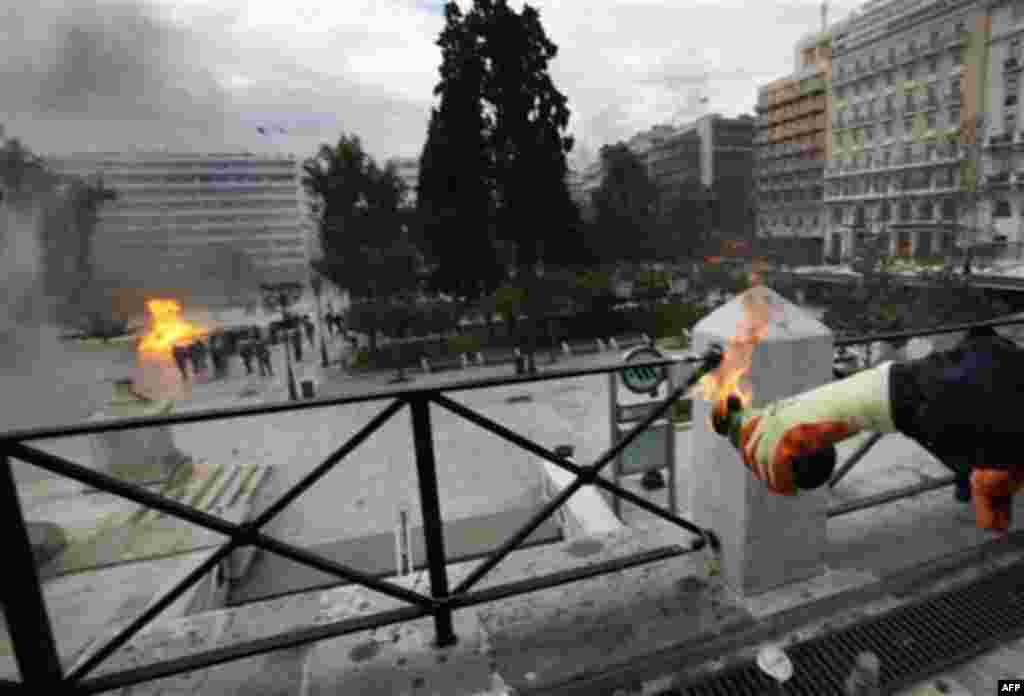 A protester wearing an anti-flame glove prepares to throw a petrol bomb during clashes in Athens, Wednesday, Feb. 23, 2011. Scores of youths hurled rocks and petrol bombs at riot police after clashes broke out Wednesday during a mass rally taking place as