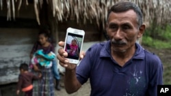 FILE - Domingo Caal Chub, 61, holds a smartphone displaying a photo of his granddaughter, Jakelin Amei Rosmery Caal Maquin, in Raxruha, Guatemala, Dec. 15, 2018. 