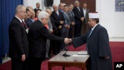 El presidente palestino Mahmoud Abbas saluda al nuevo ministro de asuntos religiosos, Youssef Daais, parte del nuevo gobierno de unidad palestino.