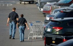 Police officers walk by shopping carts at the scene of a mass shooting at a shopping complex, Aug. 4, 2019, in El Paso, Texas.