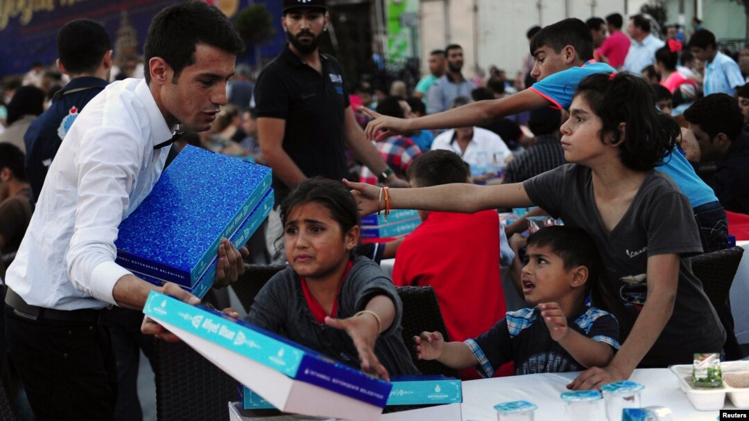 Syrian refugee children scuffle with a waiter as they try to get a pack of food at an iftar (breaking fast) event open to public during the Muslim holy fasting month of Ramadan in central Istanbul, July 17, 2014.