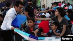 Syrian refugee children scuffle with a waiter as they try to get a pack of food at an iftar (breaking fast) event open to public during the Muslim holy fasting month of Ramadan in central Istanbul, July 17, 2014.