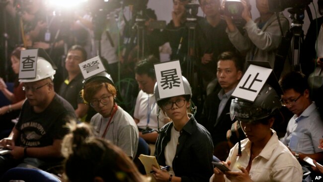 多位香港记者在2019年11月4日头戴“查警暴止警谎”标语的头盔等候警方举行记者会。