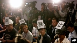 Journalists wear helmets with signs that read; "Investigate police brutality" as they protest against alleged police violence towards reporters during a police press conference in Hong Kong, Monday, Nov. 4, 2019. 