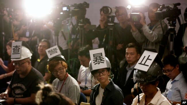 多位香港记者在2019年11月4日头戴“查警暴止警谎”标语的头盔等候警方举行记者会。