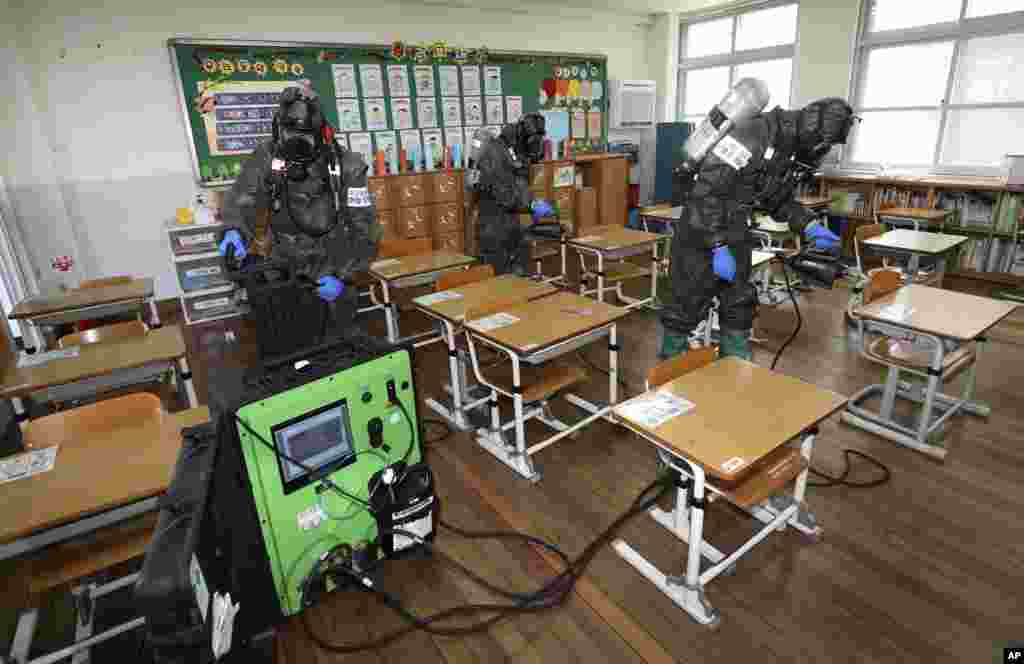 South Korean army soldiers spray disinfectant to help reduce the spread of the new coronavirus in a class at Cheondong elementary school in Daejeon.