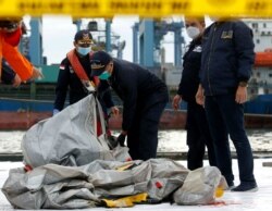 Anggota tim penyelamat membawa puing-puing pesawat Sriwijaya Air penerbangan SJ182 yang jatuh ke laut, di pelabuhan Terminal Peti Kemas Internasional Jakarta, 10 Januari 2021. (Foto: REUTERS/Ajeng Dinar Ulfiana)