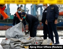 Anggota tim penyelamat membawa puing-puing pesawat Sriwijaya Air penerbangan SJ182 yang jatuh ke laut, di pelabuhan Terminal Peti Kemas Internasional Jakarta, 10 Januari 2021. (Foto: REUTERS/Ajeng Dinar Ulfiana)