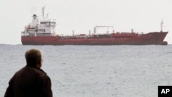 A man looks at the Saint Vincent-flagged "Chariot" cargo ship as it sails out of the port of the southern Cypriot city of Limassol, January 11, 2012.