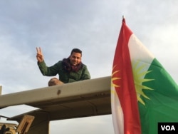 ທະຫານ Iraqi Kurdish Peshmerga ກຳລັງຍົກມືສະແດງເຖິງໄຊຊະນະ.