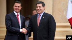 Los presidentes de México, Enrique Peña Nieto y de Paraguay, Horacio Cartes, se saludan mientras posan para fotógrafos en el Palacio de los López, en Asunción, Paraguay. Enero 18 de 2018.