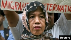 FILE - A Filipino Muslim woman joins the picket led by a migrant workers group for human rights at the embassy of the United Arab Emirates (UAE) in Manila.