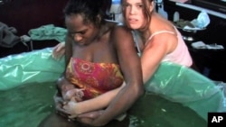 A woman gives birth at home with a midwife.