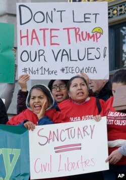 Protesters hold signs as they yell at a rally outside of City Hall in San Francisco, Jan. 25, 2017.