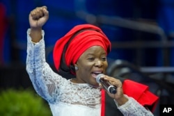 African singer Grace Alache Jerry raises her fist as she introduces President Barack Obama to speak at the Young African Leaders Initiative presidential summit in Washington, Aug. 3, 2015.