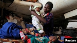 A Central African woman displaced by inter-communal violence takes care of her twin baby boys at a camp for displaced persons at Bangui M'Poko International Airport, Feb. 11, 2014.