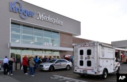 Employees wait outside the entrance of a Kroger grocery following a shooting that left two people dead and a suspect in custody in Jeffersontown, Ky., Oct. 24, 2018.