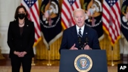 President Joe Biden speaks about his domestic agenda from the East Room of the White House in Washington, Oct. 28, 2021, as Vice President Kamala Harris looks on. Biden has been forced to make large concession on social spending.