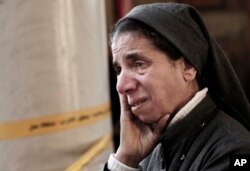 FILE - An Egyptian Coptic nun weeps as she looks at damage inside the St. Mark Cathedral in central Cairo, following a bombing,Dec. 11, 2016.