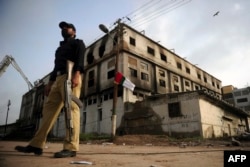 کراچی کے علاقے بلدیہ ٹاون کی گارمنٹ فیکٹری کے باہر ایک پولیس اہلکار مستعد کھڑا ہے۔ اس فیکٹری میں آگ سے جھلس کر کئی افراد ہلاک ہوئے تھے۔
