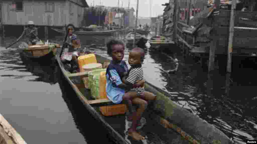 A woman paddles a canoe past illegal stilt houses in Legas that are at risk of being demolished by the government.