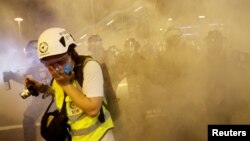 Seorang wartawan menutup wajahnya setelah para polisi menembakkan gas air mata ke arah demonstran anti RUU ekstradisi di Hong Kong, China, 4 Agustus 2019.